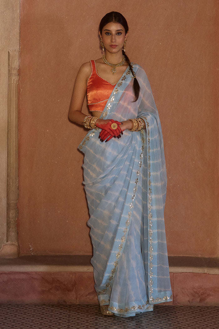 Neelima – Sky Blue Leheriya Saree with Orange Sleeveless  Blouse