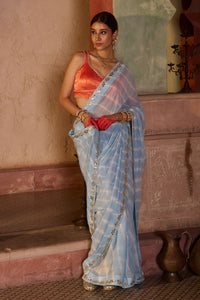 Neelima – Sky Blue Leheriya Saree with Orange Sleeveless  Blouse