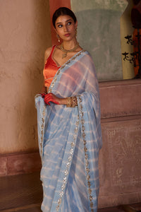 Neelima – Sky Blue Leheriya Saree with Orange Sleeveless  Blouse