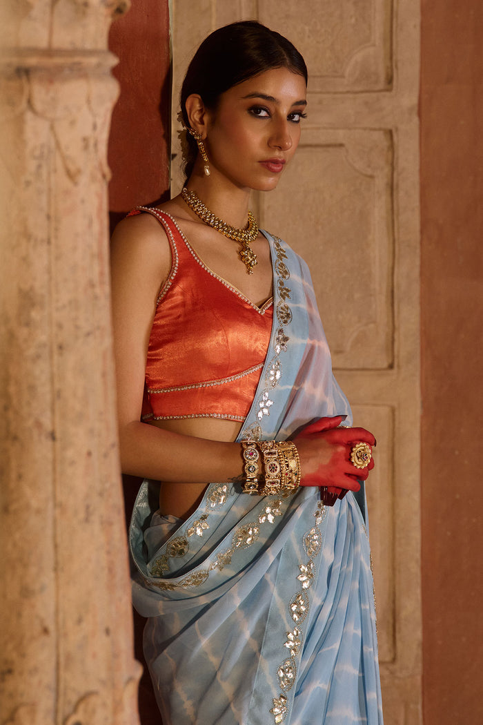 Neelima – Sky Blue Leheriya Saree with Orange Sleeveless  Blouse